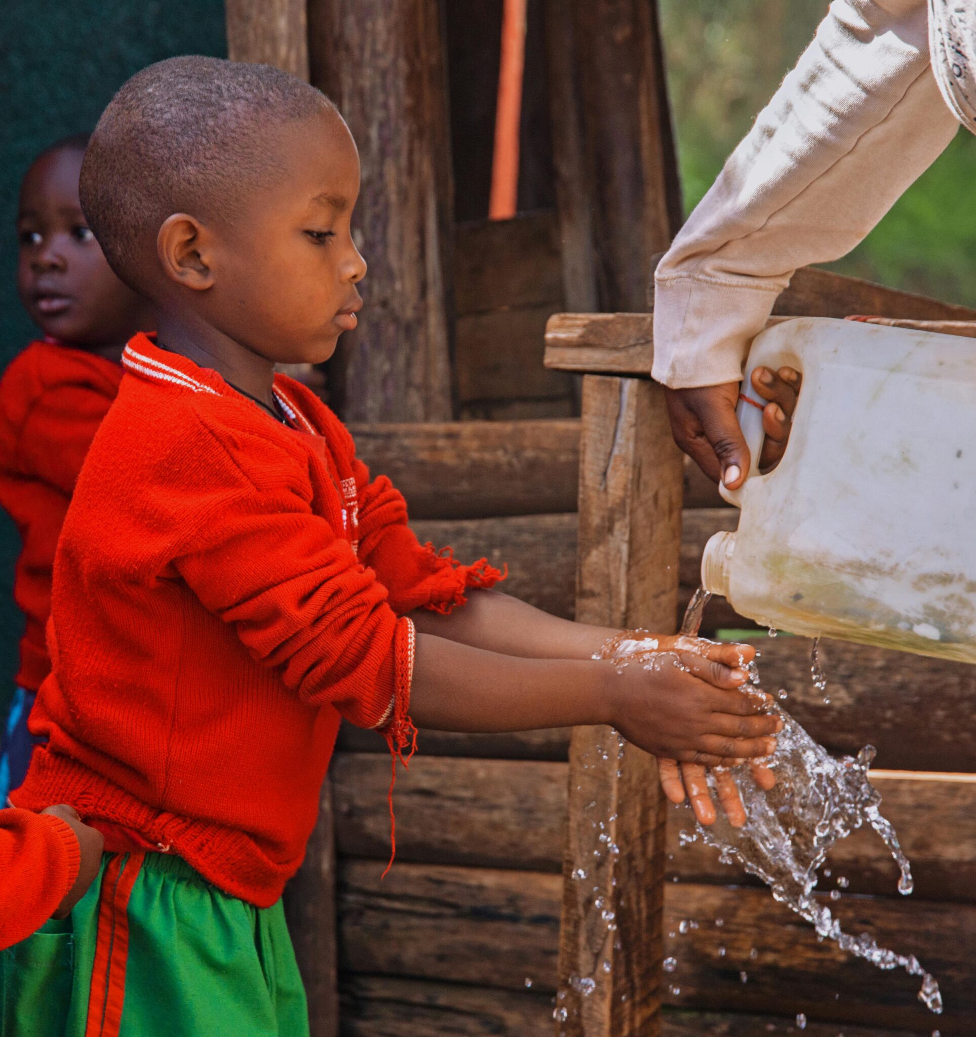 Young child washing hands in a rural area of Uganda, promoting hygiene awareness.